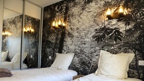 A hotel room with two beds, a large mirror, and a wall mural.