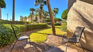 An outdoor seating area with two chairs, a well-maintained lawn, and palm trees. - Escape to the beach! (Destin)