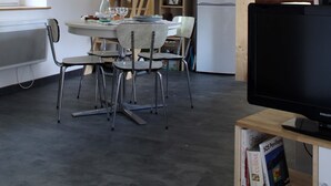Eine moderne Küche mit Essbereich, einer Holztreppe und einem Fernseher auf einem Holzboden.