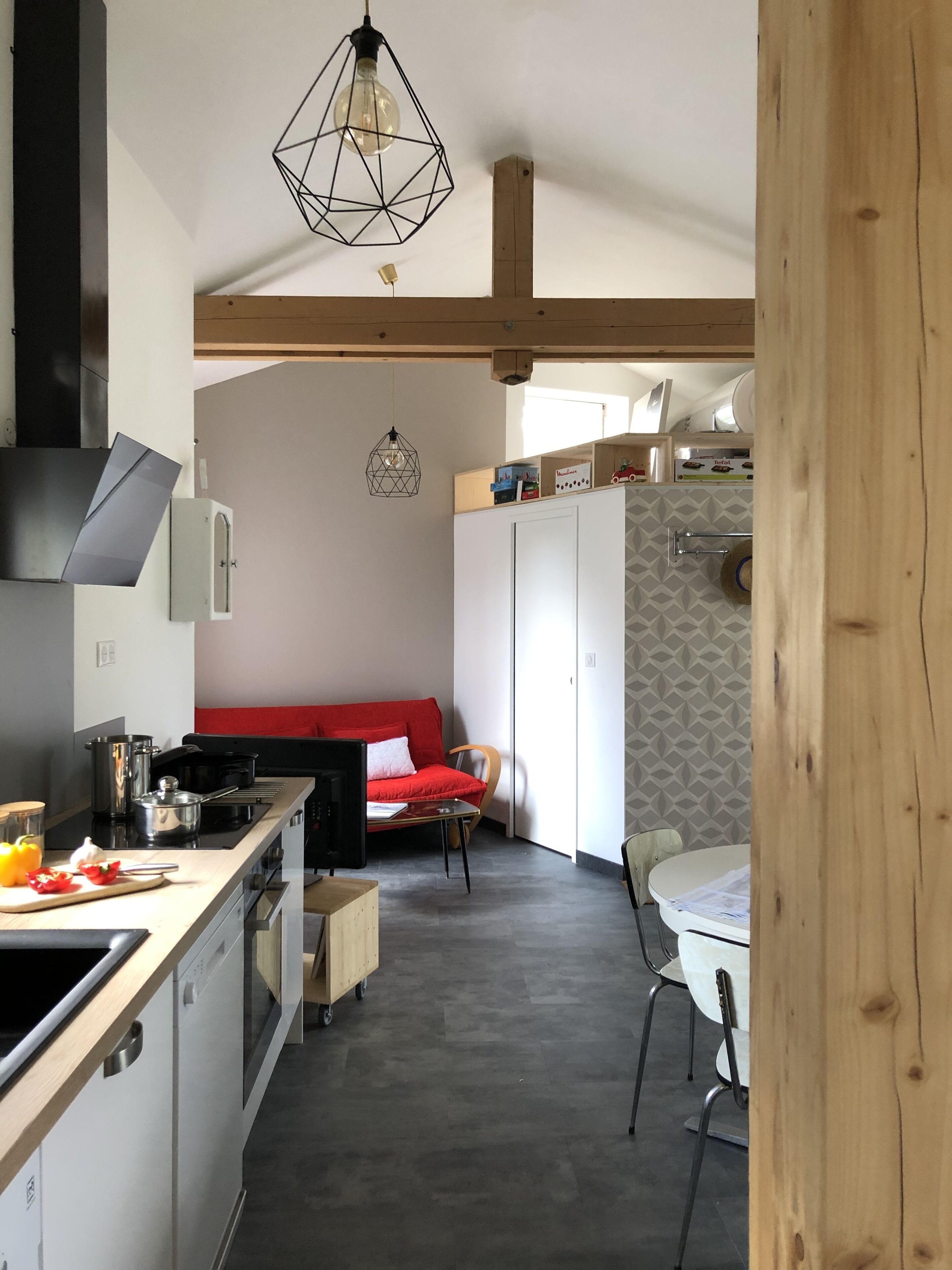 Een moderne keuken met een rode bank, een eethoek en een houten plafond.