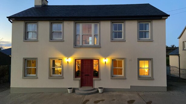A two-story house with a red door, multiple windows, and exterior lighting. - Scenic Estuary Way 3-bed Home in Labasheeda (Labasheeda)