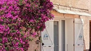 A building with a white door and a 'Welcome' sign, a small red table, and a yellow chair outside. - "A CUSTOM NEST by the sea! " (Lucciana)
