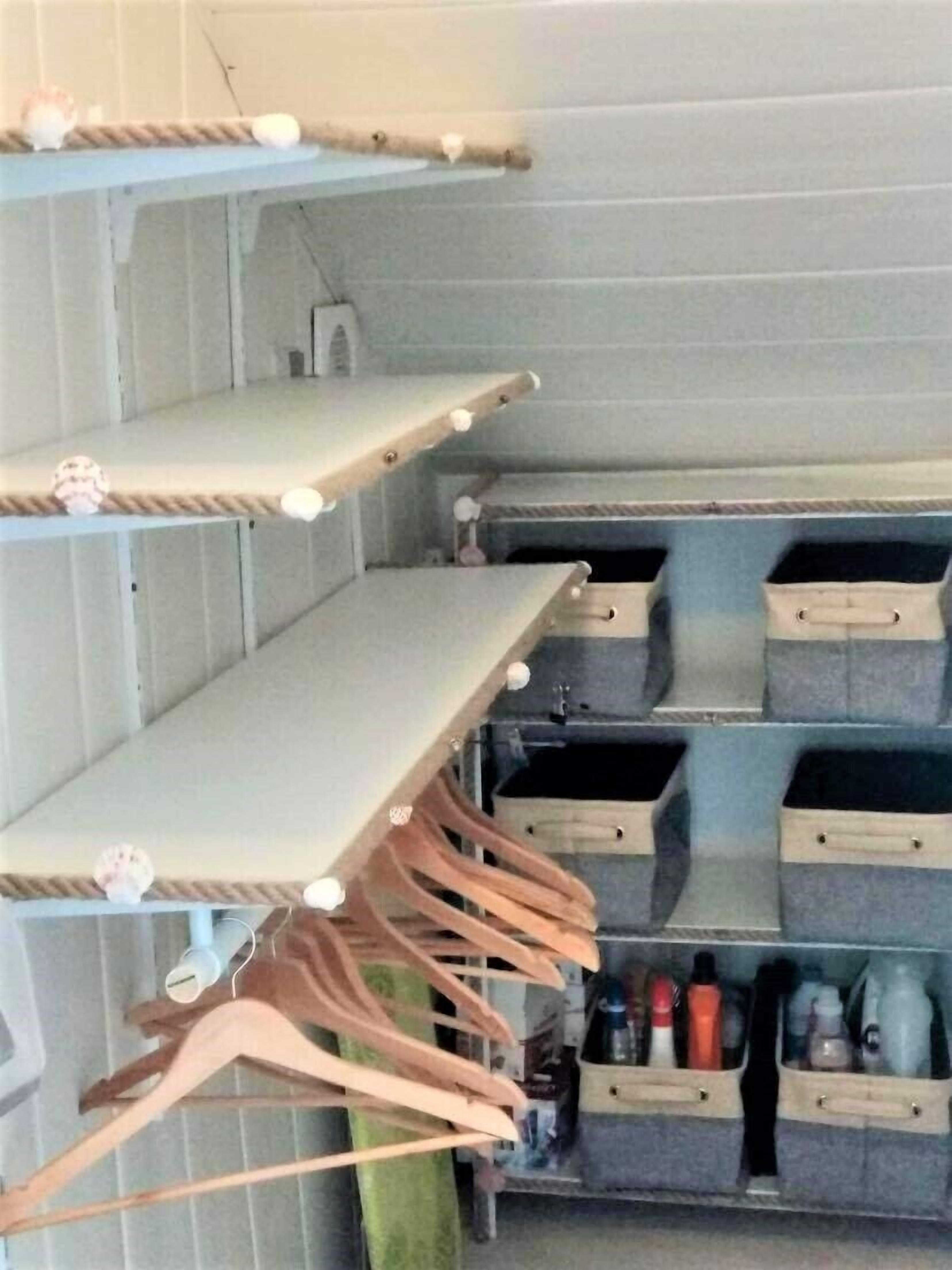 Ein Stauraum mit Regalen, Holzaufhängern und Aufbewahrungsbehältern.