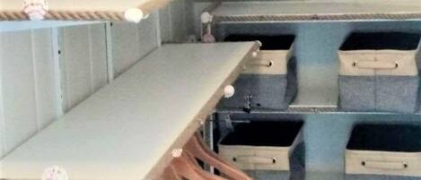 Ein Stauraum mit Regalen, Holzaufhängern und Aufbewahrungsbehältern.