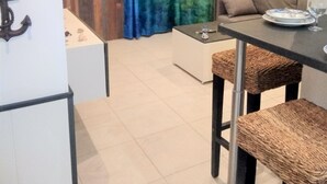 A small, cozy room with a dining table and chairs, a sofa, and a curtain with a scenic view. - "A CUSTOM NEST by the sea! " (Lucciana)