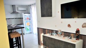 A modern kitchen with a dining area, a TV mounted on the wall, and decorative rocks on the counter. - "A CUSTOM NEST by the sea! " (Lucciana)