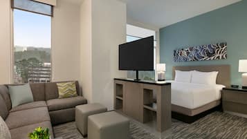 Una habitación de hotel moderna con una cama grande, un sofá, un televisor y un escritorio.
