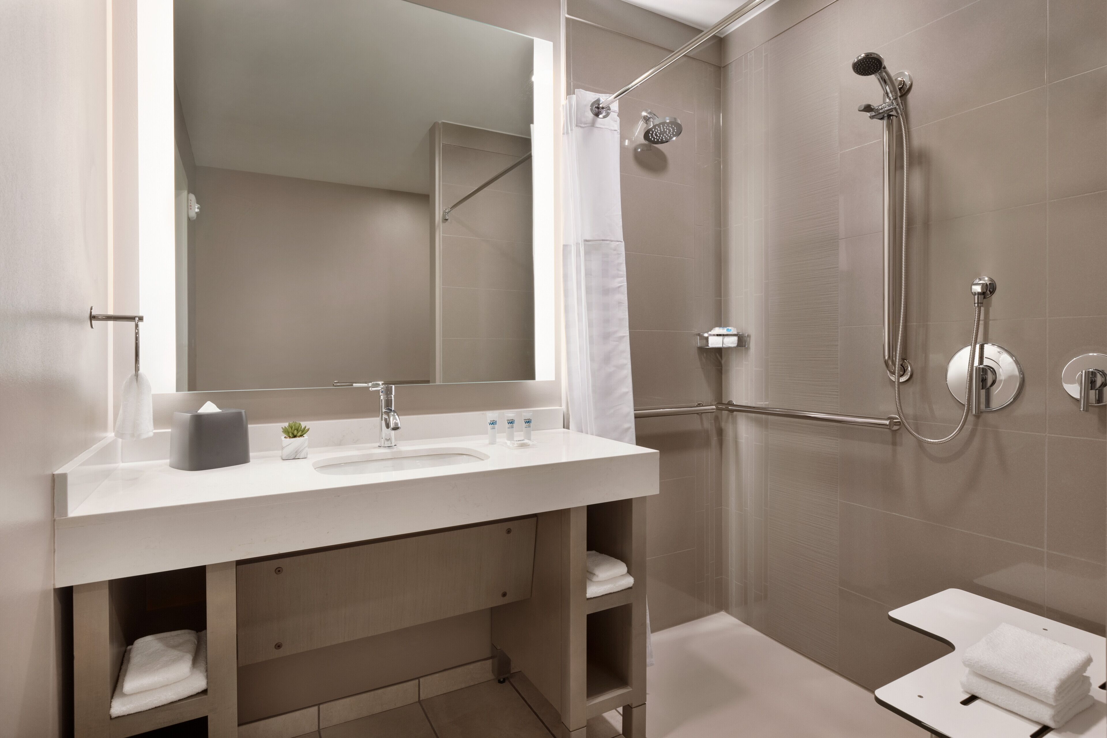 A modern bathroom with a white sink, mirror, and shower.