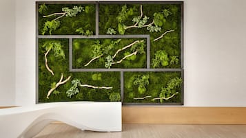 Contemporary space features a large wall-mounted display with six panels showcasing lush greenery and branches.