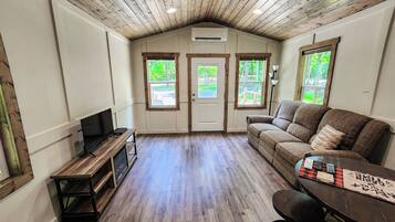 A cozy room with a wooden ceiling, a couch, a TV, and a table with a placemat.