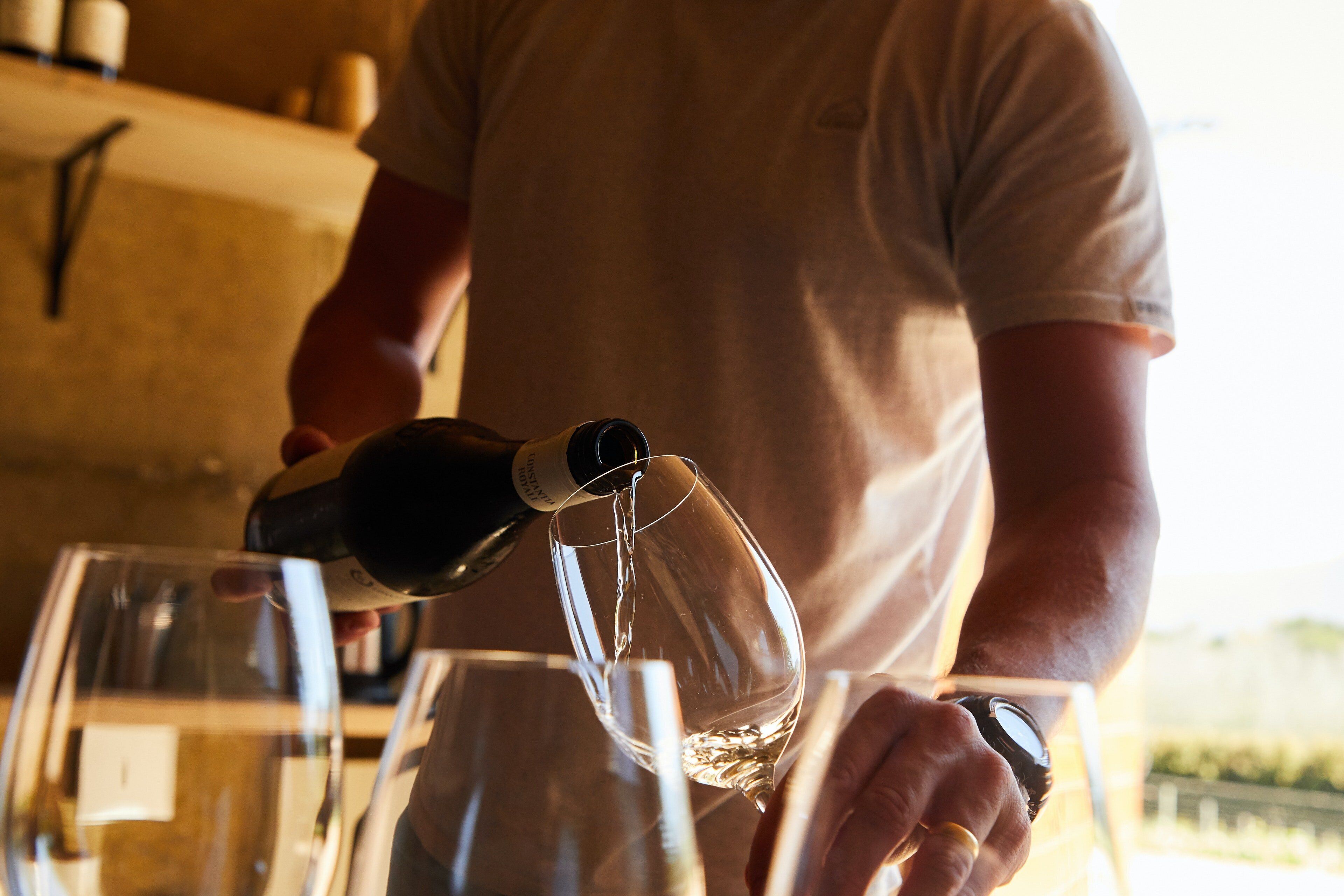 A person pouring a clear liquid into a glass.