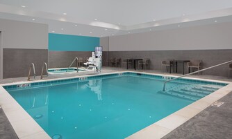 Una piscina interior con trampolín, sillas de descanso y una silla para salvavidas.