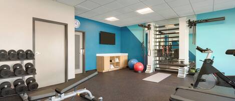 A gym with exercise equipment, a wall clock, and a door.