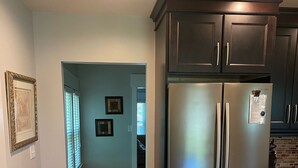 Una cocina con refrigerador de acero inoxidable, piso de madera y gabinetes oscuros.