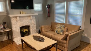 Una sala de estar con chimenea, un sofá, una mesa de centro y un televisor montado en la pared.
