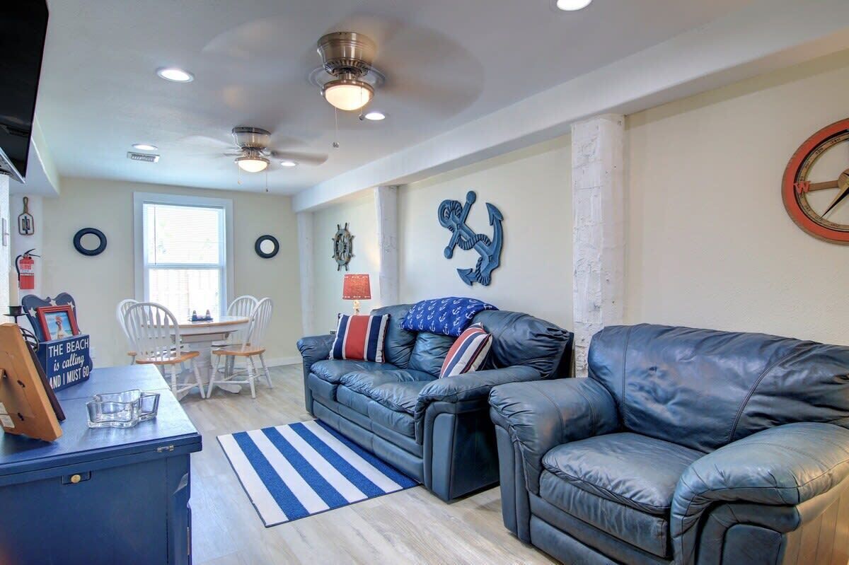 A living room with a blue leather sofa, a coffee table, and a dining area with chairs.