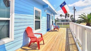Ein blaues Haus mit Veranda, roten Stühlen und einer Texas-Flagge.