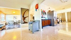 A spacious lobby with a polished floor, a large sculpture, a seating area, and a kitchen area with a refrigerator and shelves. - 3 Bedroom 3 Bath  a waterfront 3 Acre Home close to Downtown and Beaches. (Fort Pierce)
