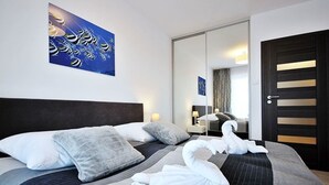 A hotel room with a large bed, a mirror, a door, and a painting on the wall. - Apartment Kolberg 10 Minutes Walk From the Beach (Kolobrzeg)