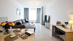 A modern hotel room with a sofa, dining table, and a TV. - Apartment Kolberg 10 Minutes Walk From the Beach (Kolobrzeg)