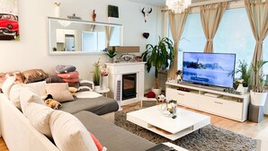 Ein modernes Wohnzimmer mit Sofa, Couchtisch, Fernseher, Kamin und Dekorationselementen.