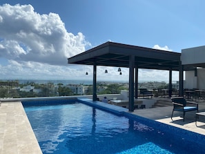 Una piscina en la azotea con vistas a la ciudad y al océano.