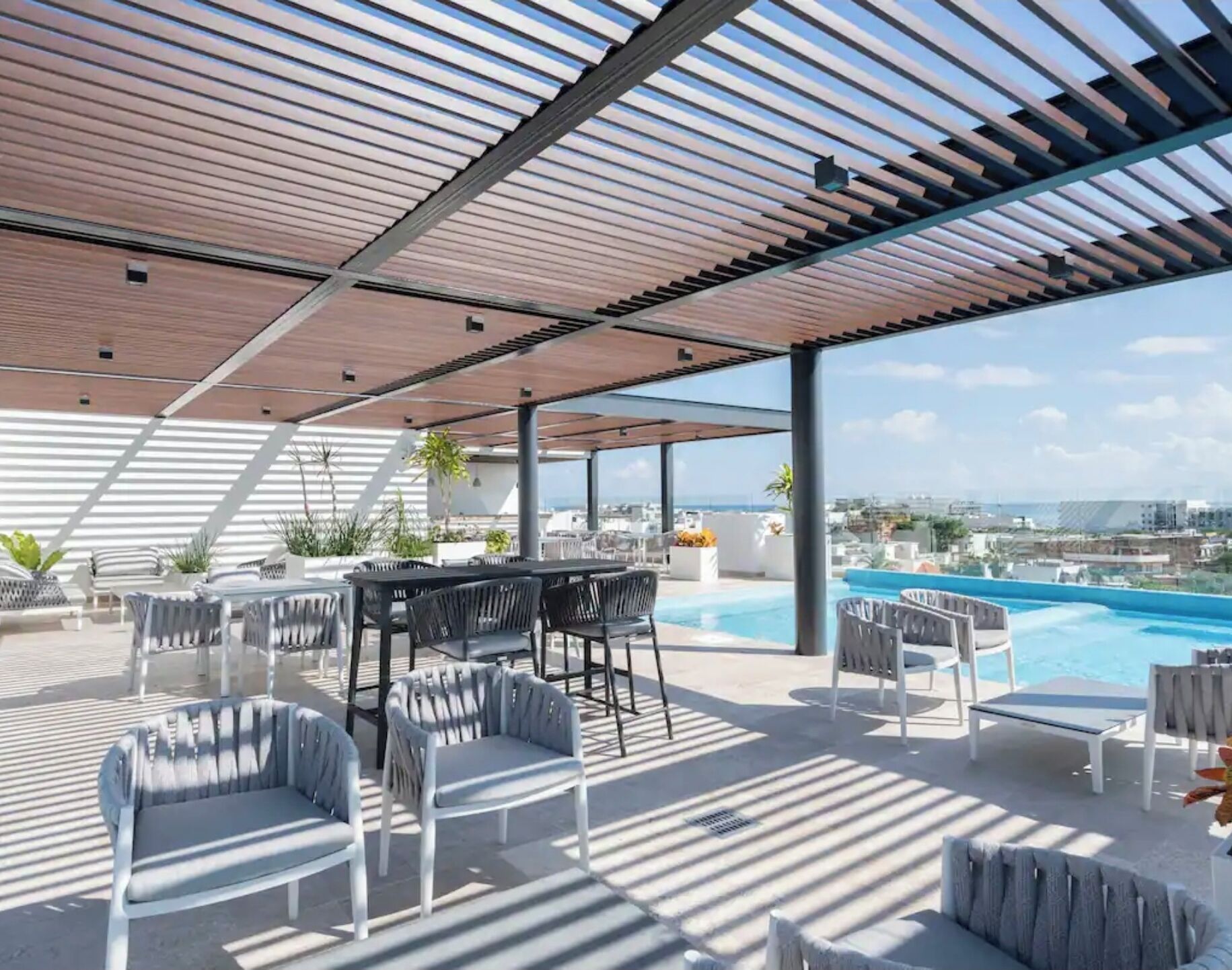 A rooftop terrace with a pool, outdoor seating, and a view of the city.