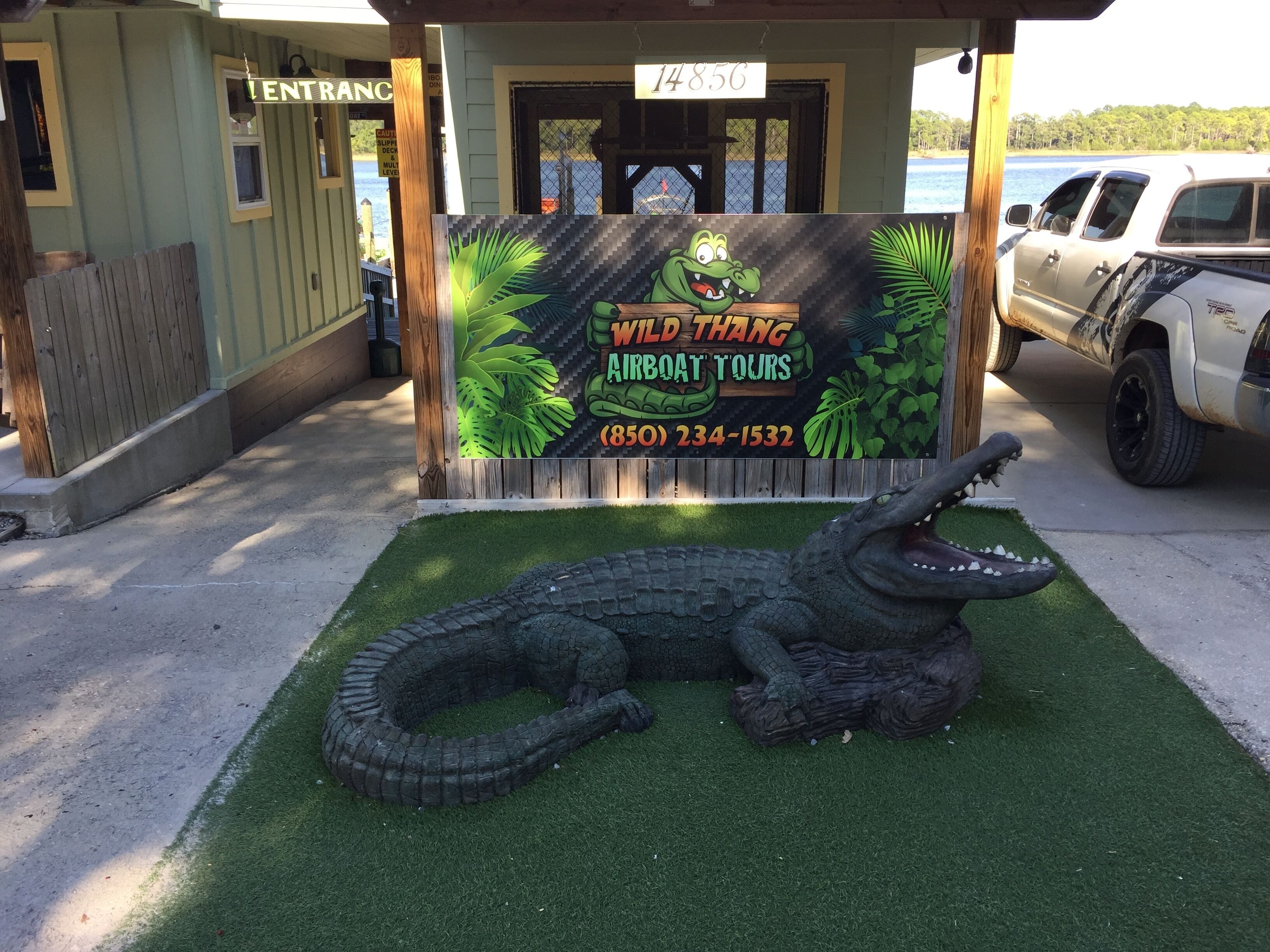 A sign for Wild Thang Airboat Tours with a crocodile sculpture in front.