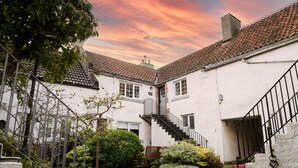 A courtyard with a white building, a staircase, and potted plants. - No. 60 Crail, stylish and new (Crail)