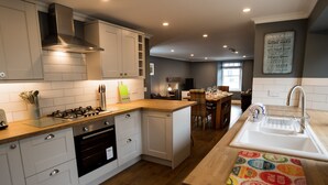 A modern kitchen with white cabinetry, a gas stove, and a wooden countertop. - No. 60 Crail, stylish and new (Crail)