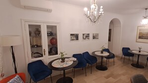 Ein Zimmer mit Essbereich, ausgestattet mit blauen Stühlen und runden Tischen, einer Kristallleuchtre und einem Schrank mit Glastüren.