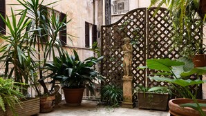 A courtyard with potted plants, a statue, and a lattice gate. - Casa Linnéa Vacanze, Central apartment, WIFI, Printer & Scanner, A/C, heating (Roma)