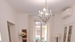 A spacious living room with a chandelier, a dining area with chairs, a table, and a view of the outside through a window. - Casa Linnéa Vacanze, Central apartment, WIFI, Printer & Scanner, A/C, heating (Roma)