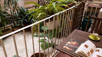 Un balcone con un tavolo di legno, una tazza verde e un libro.