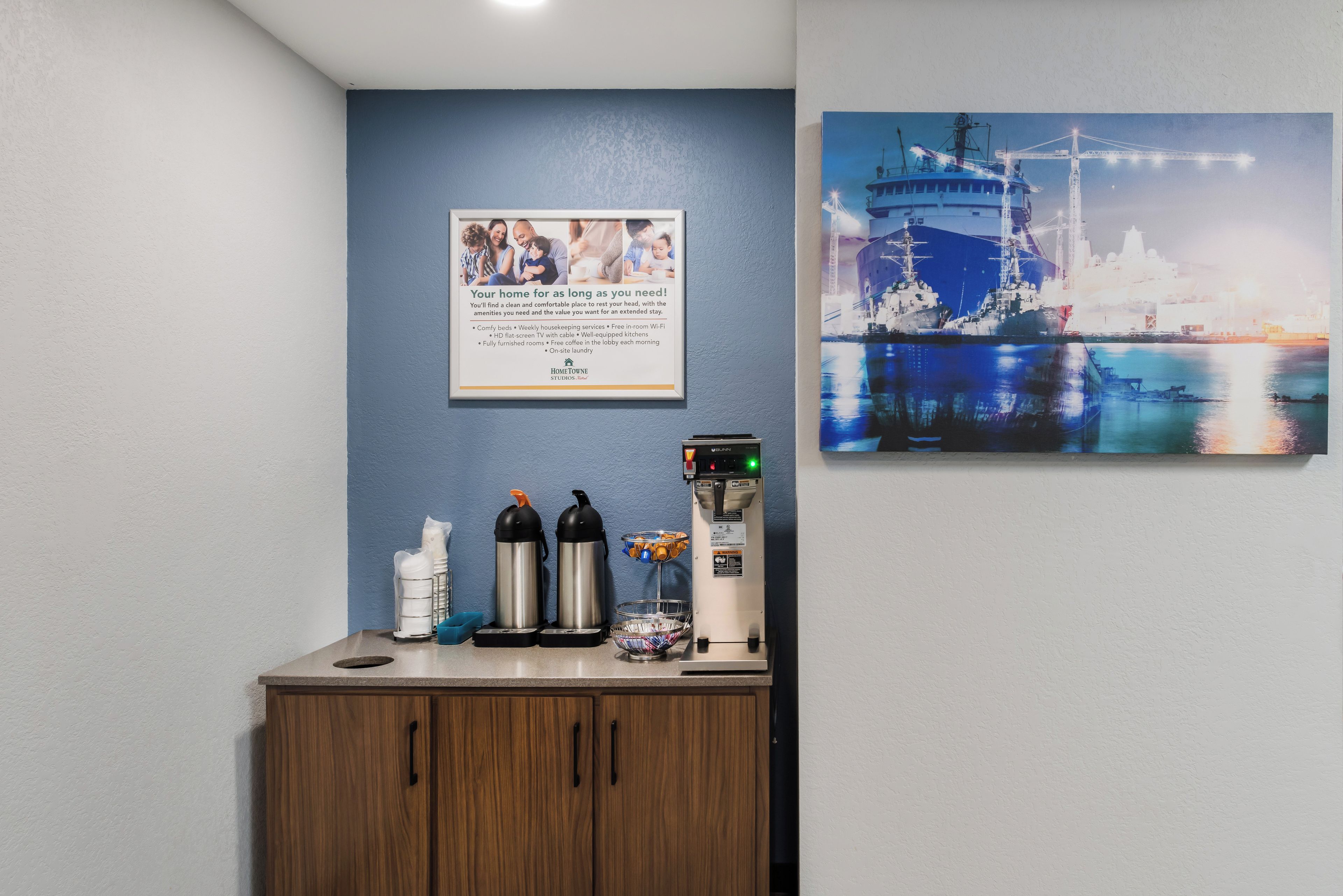 Une pièce propre et bien éclairée, avec une affiche explicative encadrée, une machine à café et un distributeur d’eau sur un comptoir.