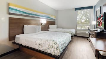 A hotel room with two beds, a desk, and a television.