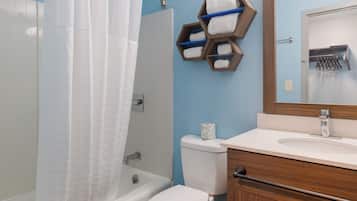 Une salle de bain équipée d’un rideau de douche, de toilettes, d’un lavabo et d’un porte-serviettes doté d’étagères hexagonales.