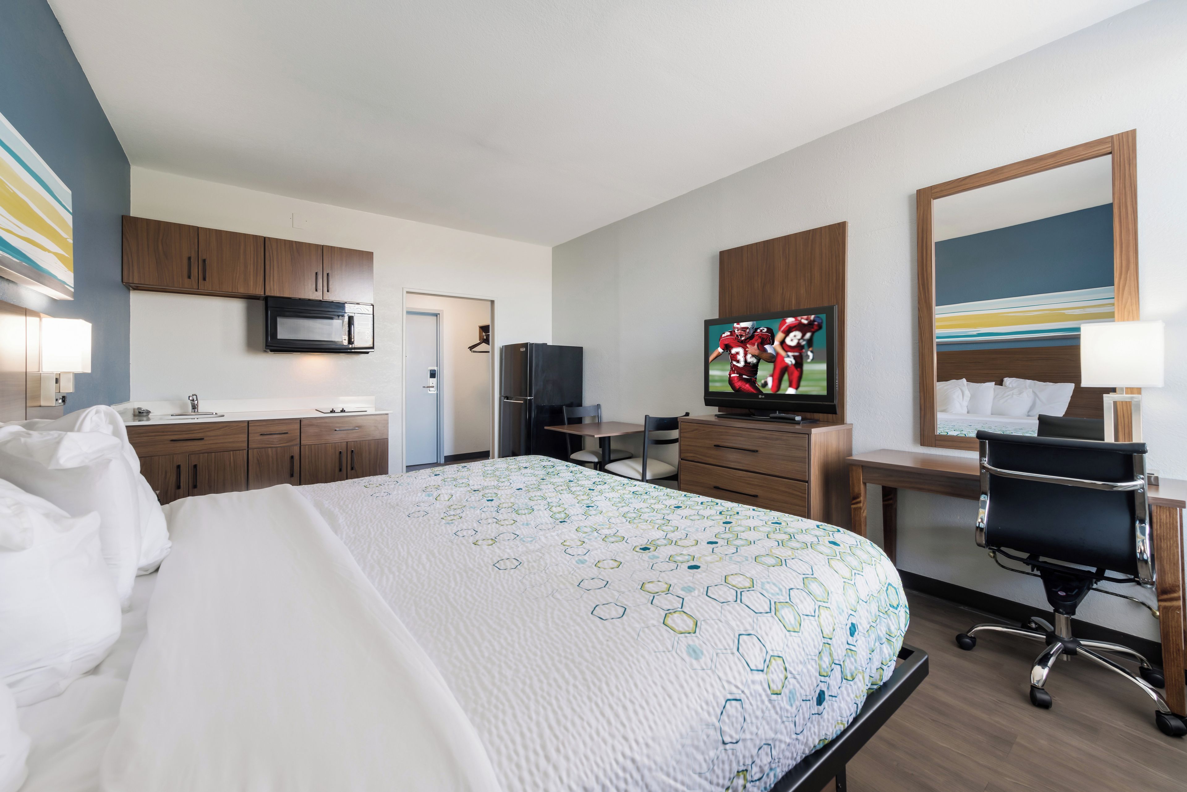 Une chambre d’hôtel équipée d’un lit, d’un bureau, d’une télévision, d’un four à micro-ondes et d’un réfrigérateur.