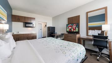 Quarto de hotel com cama, escrivaninha, televisão, micro-ondas e frigorífico.