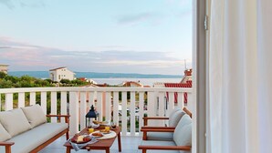 En balkon med et bord dækket til morgenmad, med udsigt over kysten, bygninger og havet.