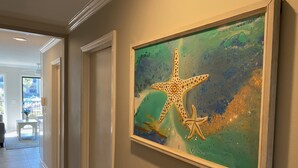 Un passadís amb una obra d'art emmarcada que mostra una estrella de mar i una estrella de mar més petita sobre un fons rugós.