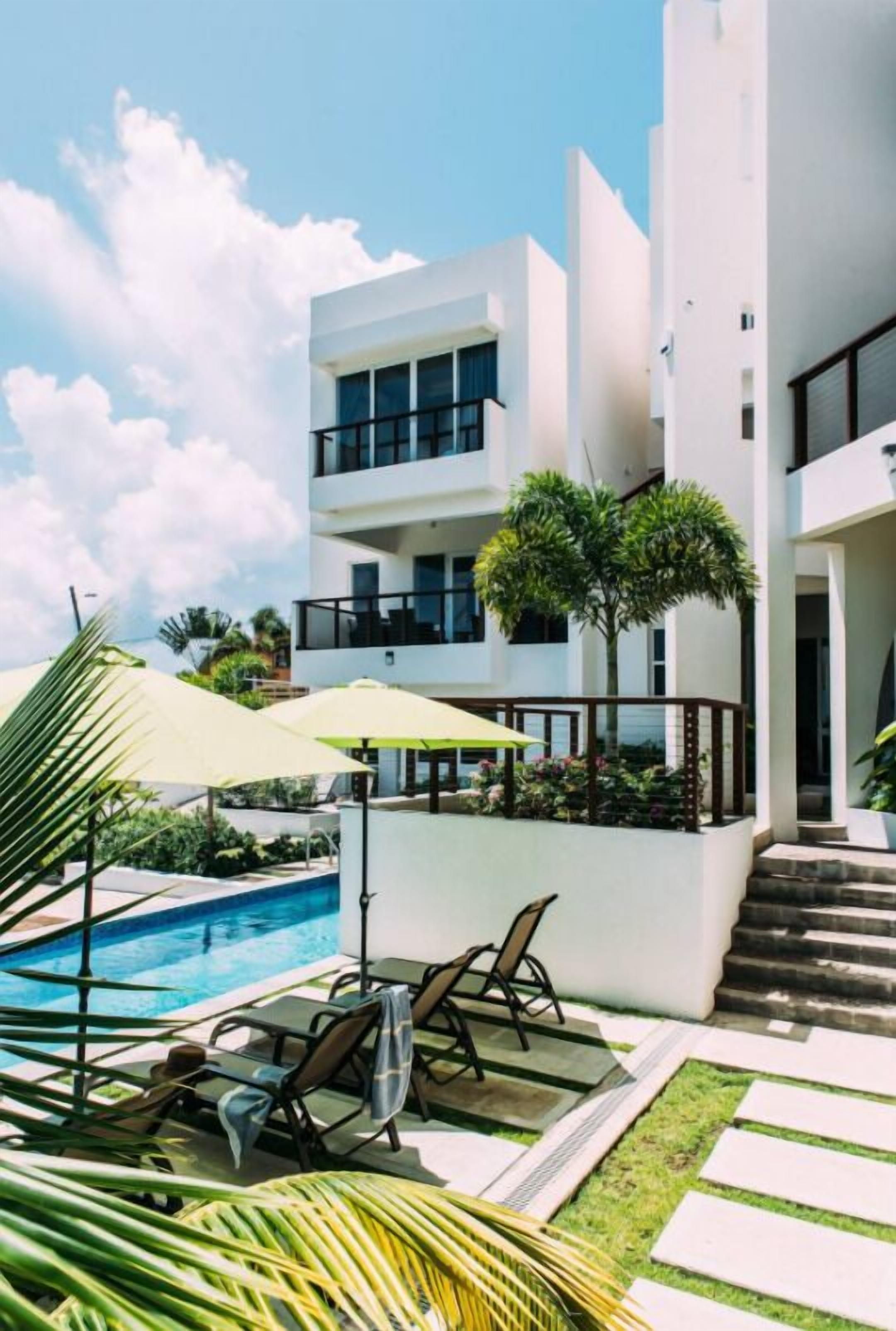 A modern hotel with a swimming pool, outdoor seating, and a well-maintained garden.