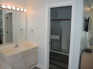 A bathroom with a large mirror, vanity, and a shower area with a glass door. - 503 2 Bedroom Villa by RedAwning (Calabash)