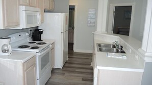 A compact kitchen with white appliances, a coffee maker, and a sink. - 503 2 Bedroom Villa by RedAwning (Calabash)