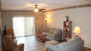 Una sala de estar con sofá, reposapiés, mesa de centro y estantería.
