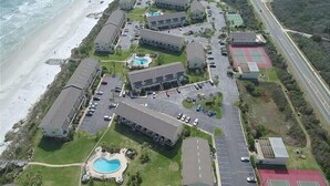 Vista aérea de un hotel costero con varias edificaciones, un estacionamiento y una playa.
