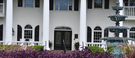 A stately building with a large entrance, numbered 380, flanked by white columns and a multi-tiered fountain.