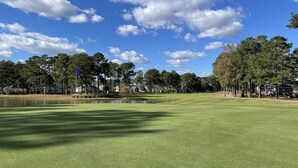 A golf course with a pond, trees, and houses in the background. - 2705 2 Bedroom Villa by RedAwning (Calabash)