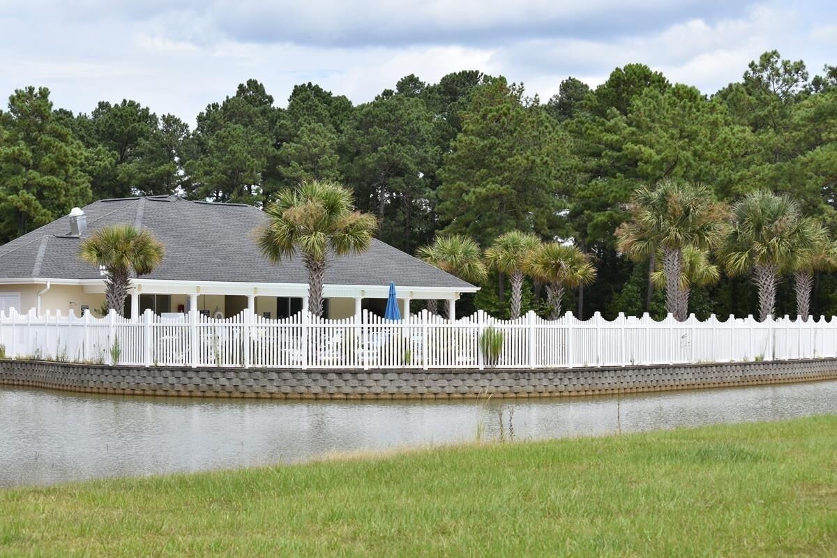 A house with a white picket fence, a covered porch, and palm trees.