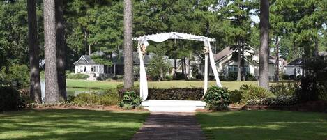A gazebo in a well-maintained garden with a brick pathway leading to it.